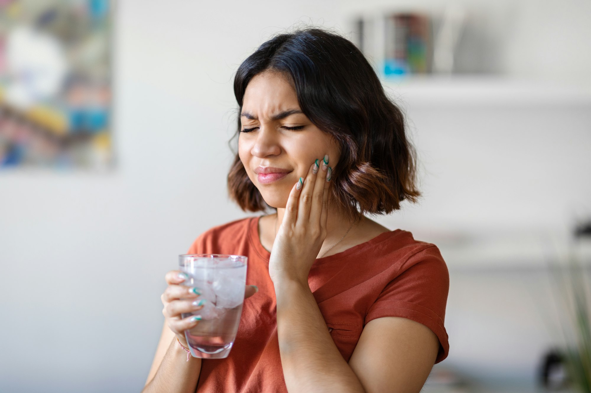 Sensitive Teeth. Young arab woman drinking water with ice and touching cheek